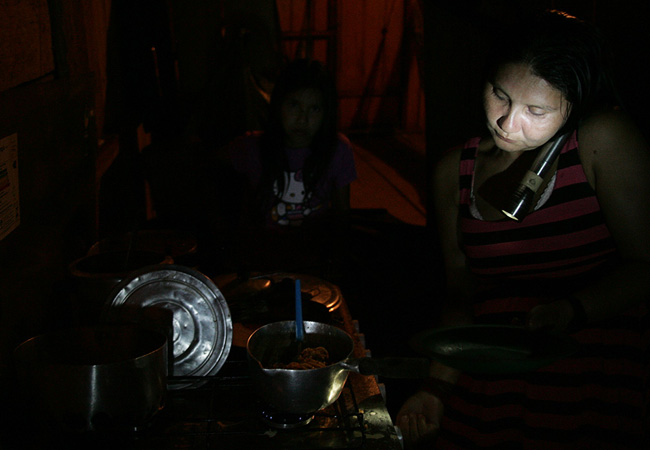 Sem energia, Maitá prepara a comida com lanterna (Foto: Odair Lima/AR) 
