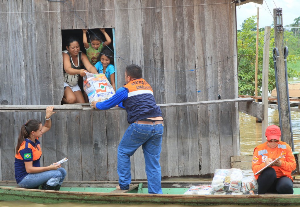 Agentes da Defesa Civil usam canoa para entregar alimentos as famílias em Canutama em 2015 (Danilo Mello/FotoAmazonas)