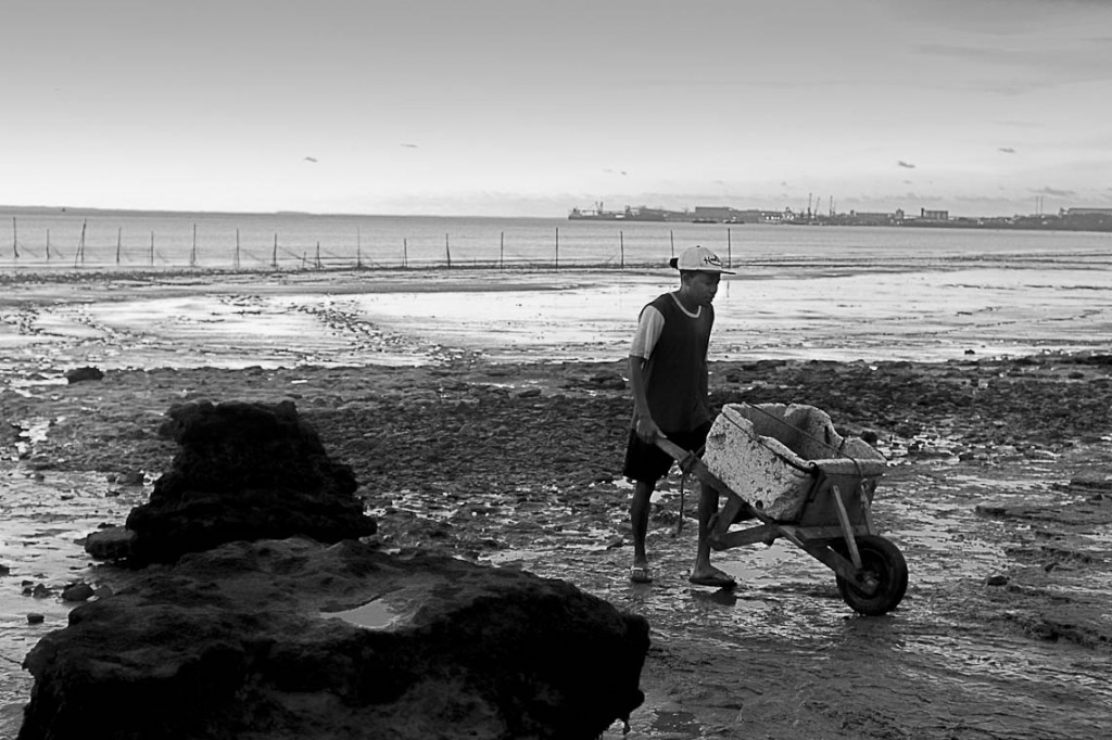 Pescadores trabalham na Praia do Cajueiro, no horizonte o Porto de Itaqui (Foto: Ana Mendes/Amazônia Real)