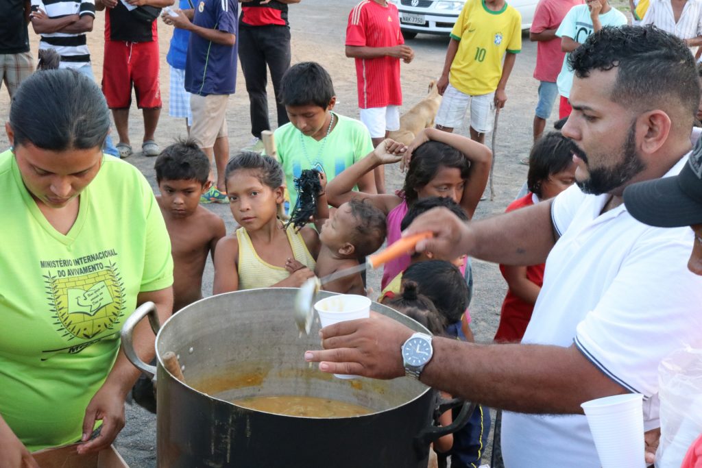 Voluntário entrega sopa para migrantes Warao em Boa Vista (Foto: Vandré Fonseca/Amazônia Real) 